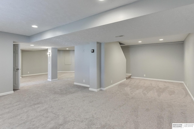 basement featuring a textured ceiling and light carpet