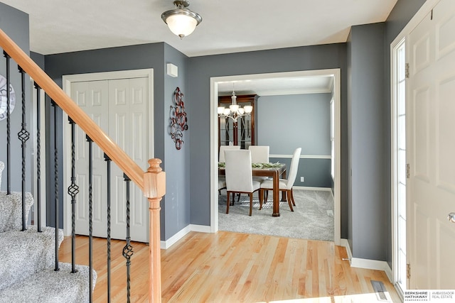 foyer with an inviting chandelier, light hardwood / wood-style flooring, and ornamental molding