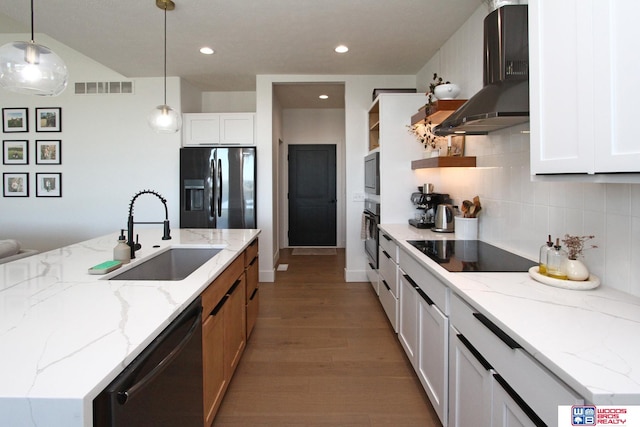 kitchen featuring black appliances, white cabinets, wall chimney range hood, and decorative light fixtures