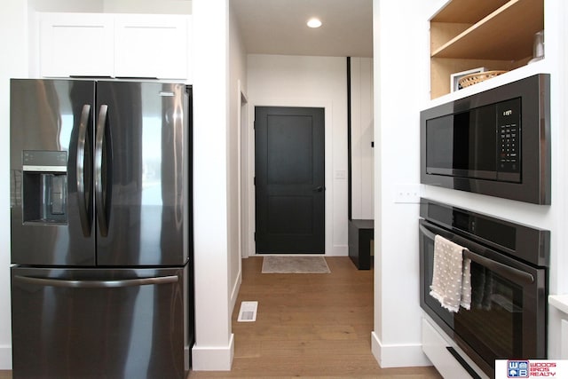 kitchen with stainless steel refrigerator with ice dispenser, white cabinetry, light hardwood / wood-style flooring, oven, and built in microwave