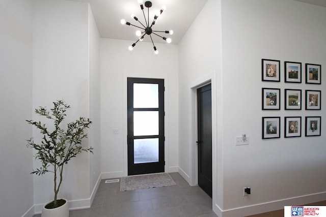 foyer entrance featuring a notable chandelier, dark tile patterned floors, and high vaulted ceiling