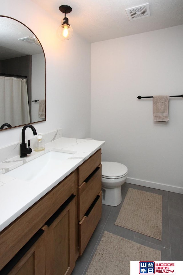 bathroom featuring vanity, tile patterned flooring, and toilet