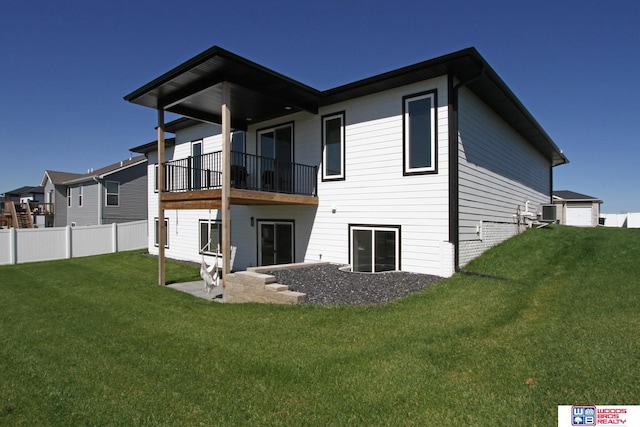 rear view of property with a lawn, a balcony, central AC unit, and a garage