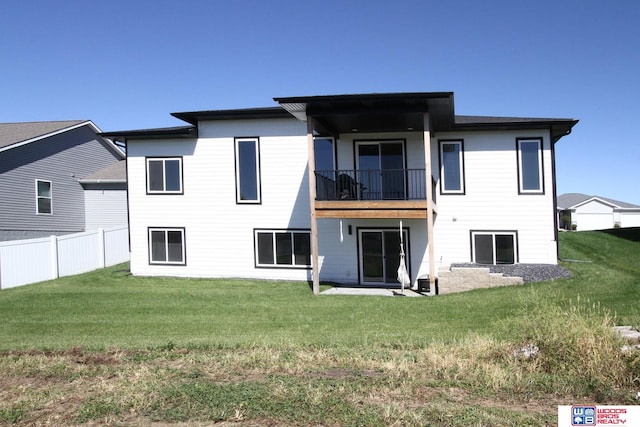 rear view of house featuring a lawn and a balcony