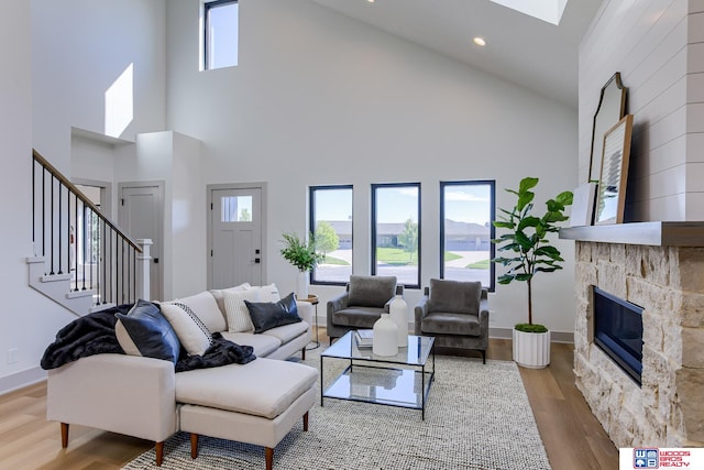 living room with high vaulted ceiling, wood-type flooring, and a stone fireplace