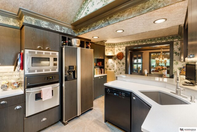 kitchen featuring appliances with stainless steel finishes, a textured ceiling, dark brown cabinetry, sink, and a notable chandelier