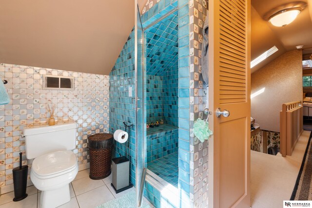 bathroom with tile walls, walk in shower, tile patterned flooring, lofted ceiling with skylight, and toilet