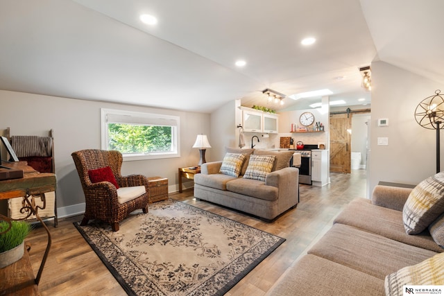 living room featuring a barn door, lofted ceiling, and light wood-type flooring