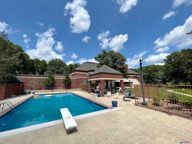 view of pool featuring a gazebo, a diving board, and a patio area