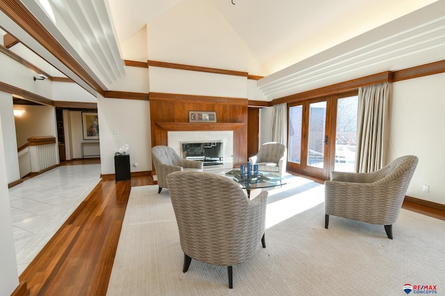 living room featuring high vaulted ceiling, ornamental molding, hardwood / wood-style floors, and french doors