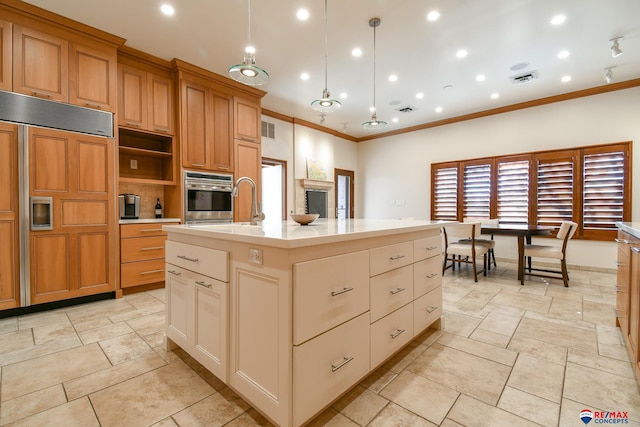 kitchen featuring pendant lighting, a kitchen island with sink, paneled built in refrigerator, crown molding, and stainless steel oven