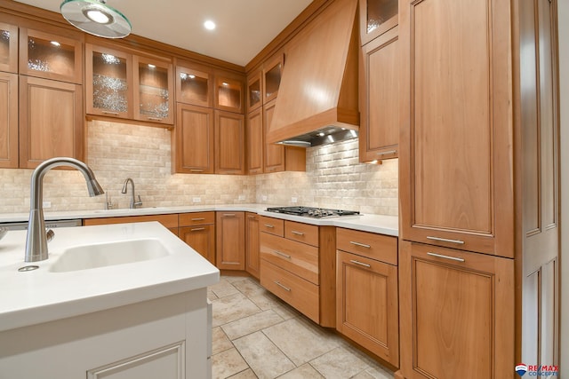 kitchen featuring stainless steel gas stovetop, backsplash, sink, and custom exhaust hood