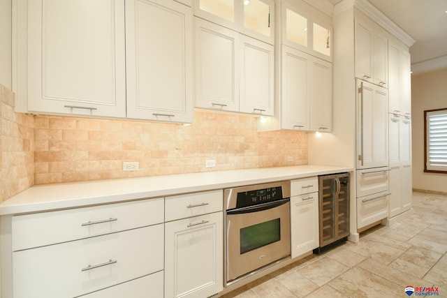 kitchen featuring decorative backsplash, oven, white cabinetry, and wine cooler