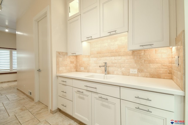 kitchen featuring backsplash, sink, and white cabinets