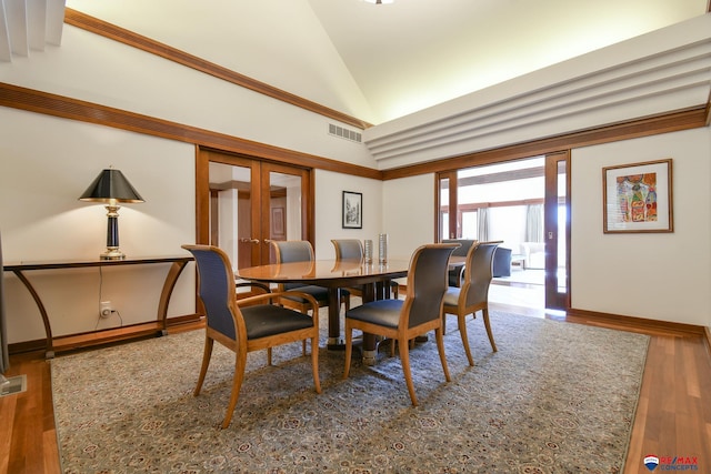 dining area with hardwood / wood-style floors and high vaulted ceiling