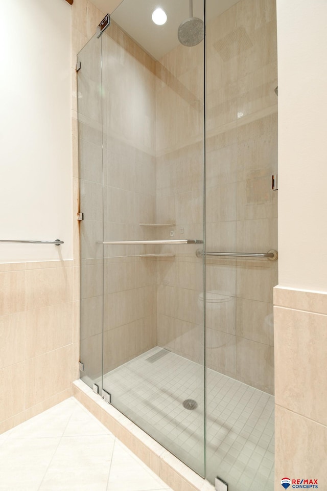 bathroom with tile walls, a shower with door, and tile patterned floors