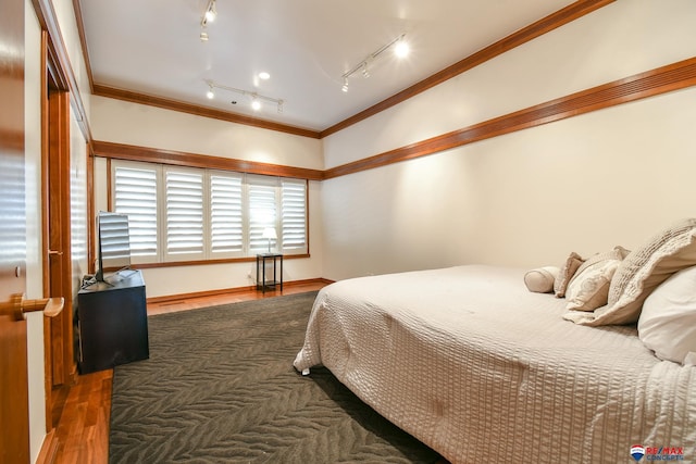 bedroom featuring ornamental molding, dark hardwood / wood-style floors, and track lighting