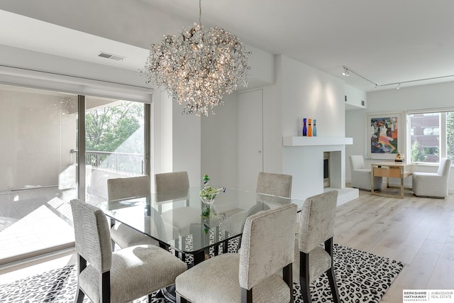 dining space with a notable chandelier, rail lighting, hardwood / wood-style floors, and plenty of natural light