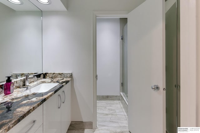 bathroom featuring a shower with shower door and vanity