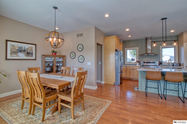 dining room featuring sink, a chandelier, and light hardwood / wood-style floors