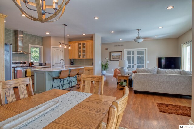 dining area featuring french doors, light wood-type flooring, plenty of natural light, and sink