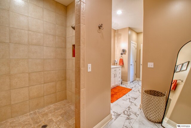 bathroom featuring tiled shower and vanity