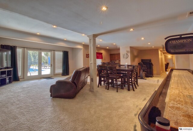 carpeted dining area featuring decorative columns and french doors