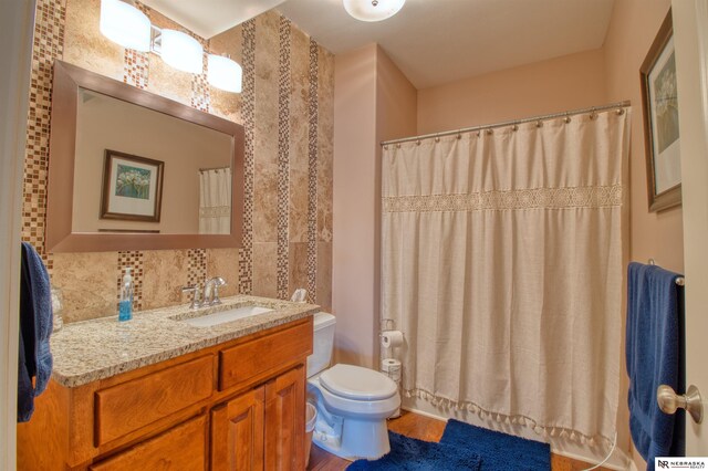 bathroom featuring vanity, toilet, and tasteful backsplash