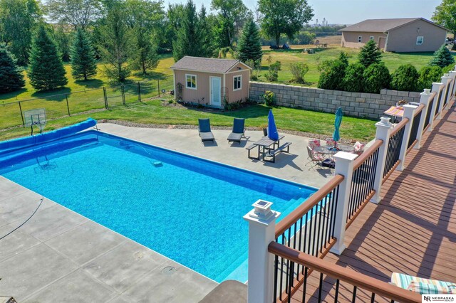 view of pool with a yard, a storage unit, and a patio area