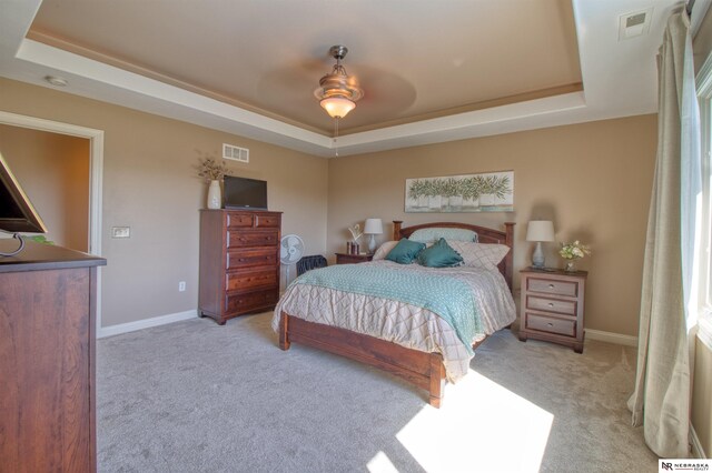 carpeted bedroom featuring ceiling fan and a tray ceiling