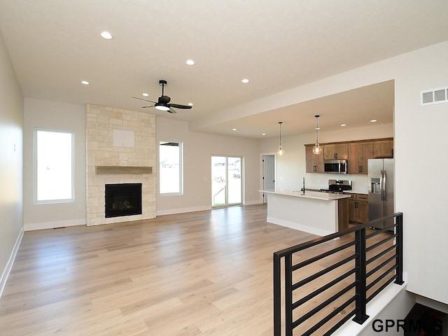 living room featuring light hardwood / wood-style floors, a fireplace, and ceiling fan