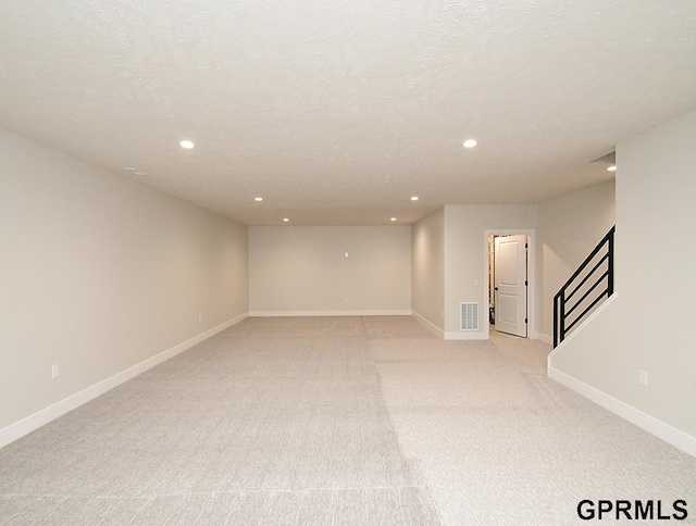 unfurnished room featuring a textured ceiling and light colored carpet