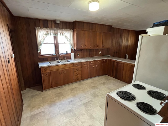 kitchen featuring white appliances, wooden walls, and sink