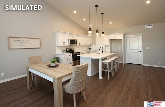 kitchen featuring appliances with stainless steel finishes, sink, pendant lighting, a center island with sink, and white cabinetry