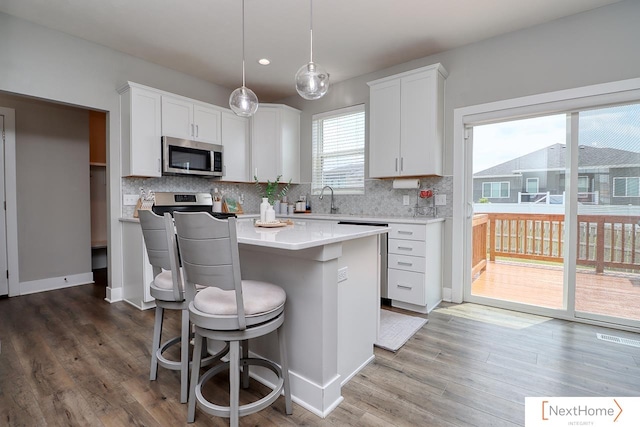 kitchen featuring white cabinets, pendant lighting, tasteful backsplash, a kitchen island, and hardwood / wood-style floors