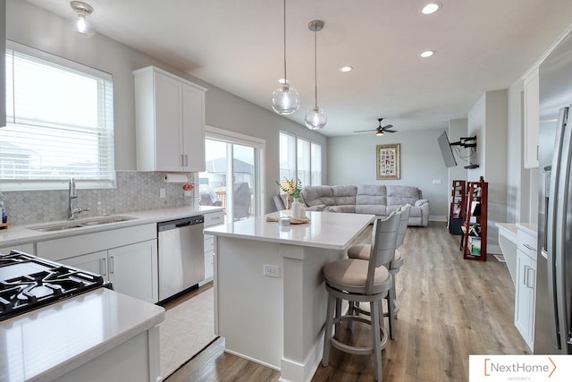 kitchen with dishwasher, a center island, sink, white cabinets, and ceiling fan