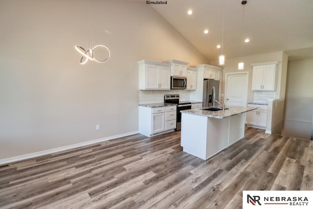 kitchen featuring white cabinets, a center island with sink, stainless steel appliances, and hanging light fixtures