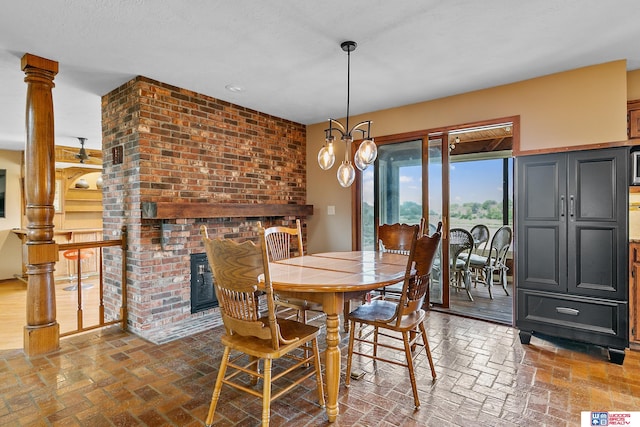 dining room featuring an inviting chandelier and a brick fireplace