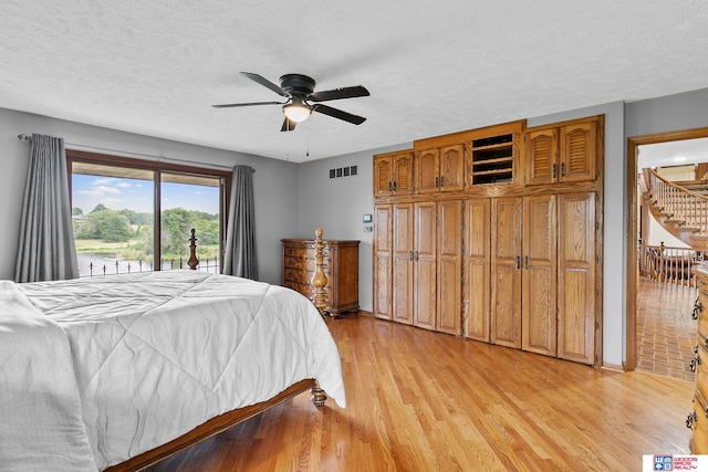 bedroom with ceiling fan, a textured ceiling, light wood-type flooring, and access to exterior