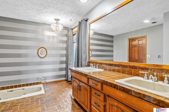 bathroom with vanity, a tub, a textured ceiling, backsplash, and a notable chandelier