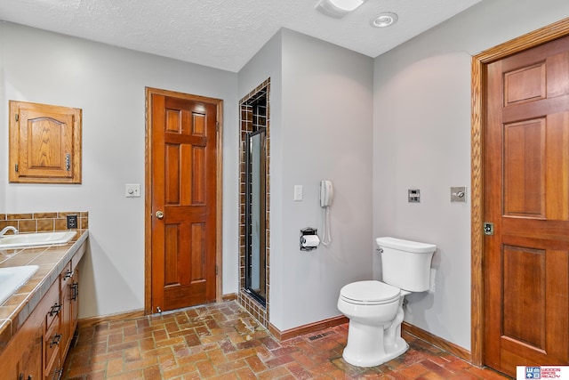 bathroom featuring vanity, a textured ceiling, an enclosed shower, and toilet