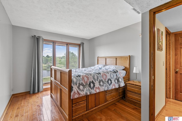 bedroom with a textured ceiling and light hardwood / wood-style flooring