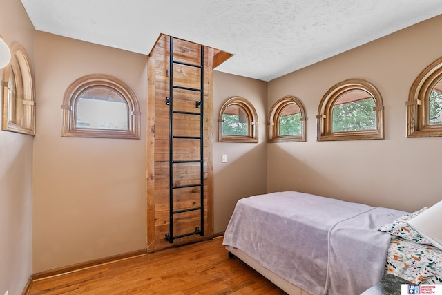 bedroom featuring light hardwood / wood-style floors, multiple windows, and a textured ceiling