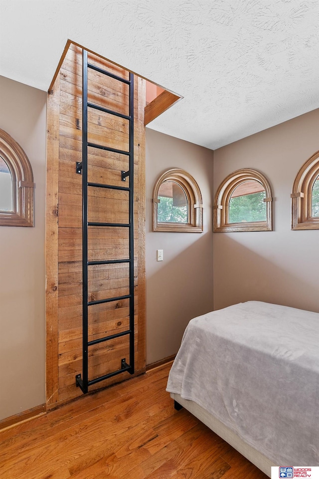 bedroom with multiple windows, hardwood / wood-style floors, and a textured ceiling