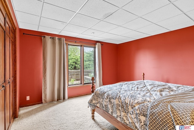 carpeted bedroom with a drop ceiling and a closet