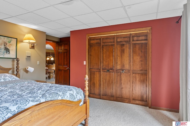 bedroom featuring light carpet, a closet, and a paneled ceiling