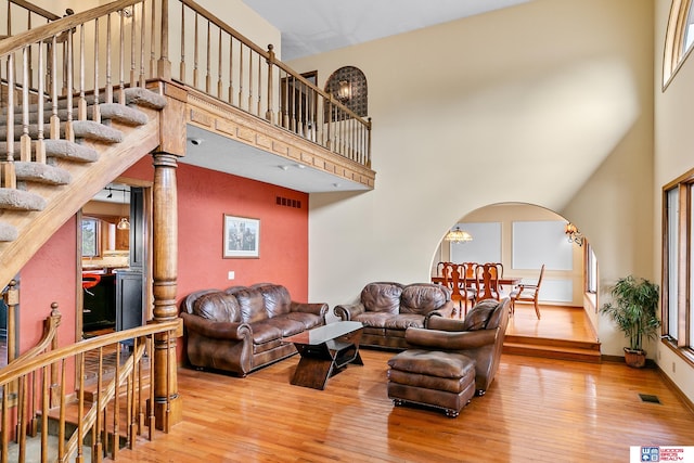 living room with a towering ceiling, wood-type flooring, and ornate columns