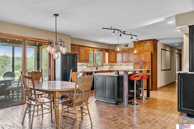 dining area with a notable chandelier, a textured ceiling, a healthy amount of sunlight, and sink