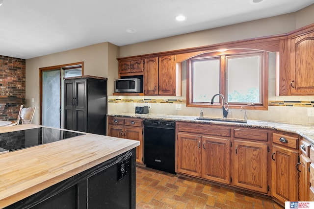 kitchen with wood counters, sink, tasteful backsplash, and black appliances