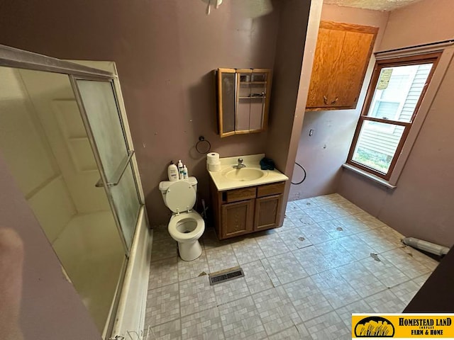 bathroom with vanity, toilet, and a shower with door